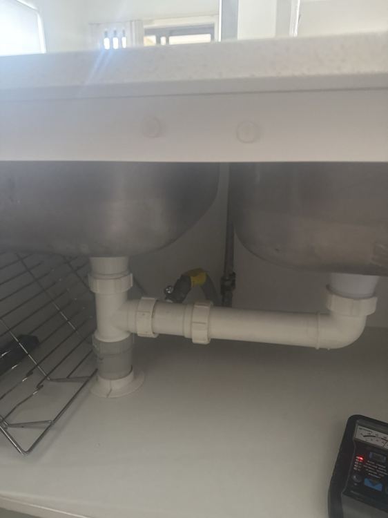 Accessible sink waste fittings and cupboard surfaces photographed.