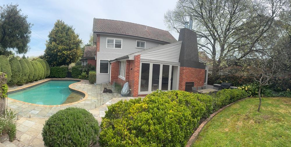 Pool and glass barrier within a residential outdoor setting